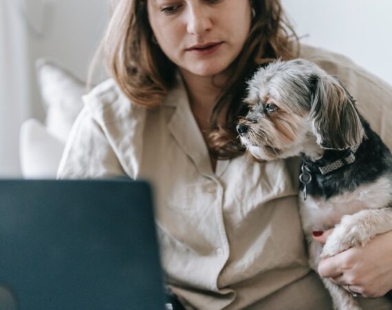 Kvinde kigger på computeren med sin hund